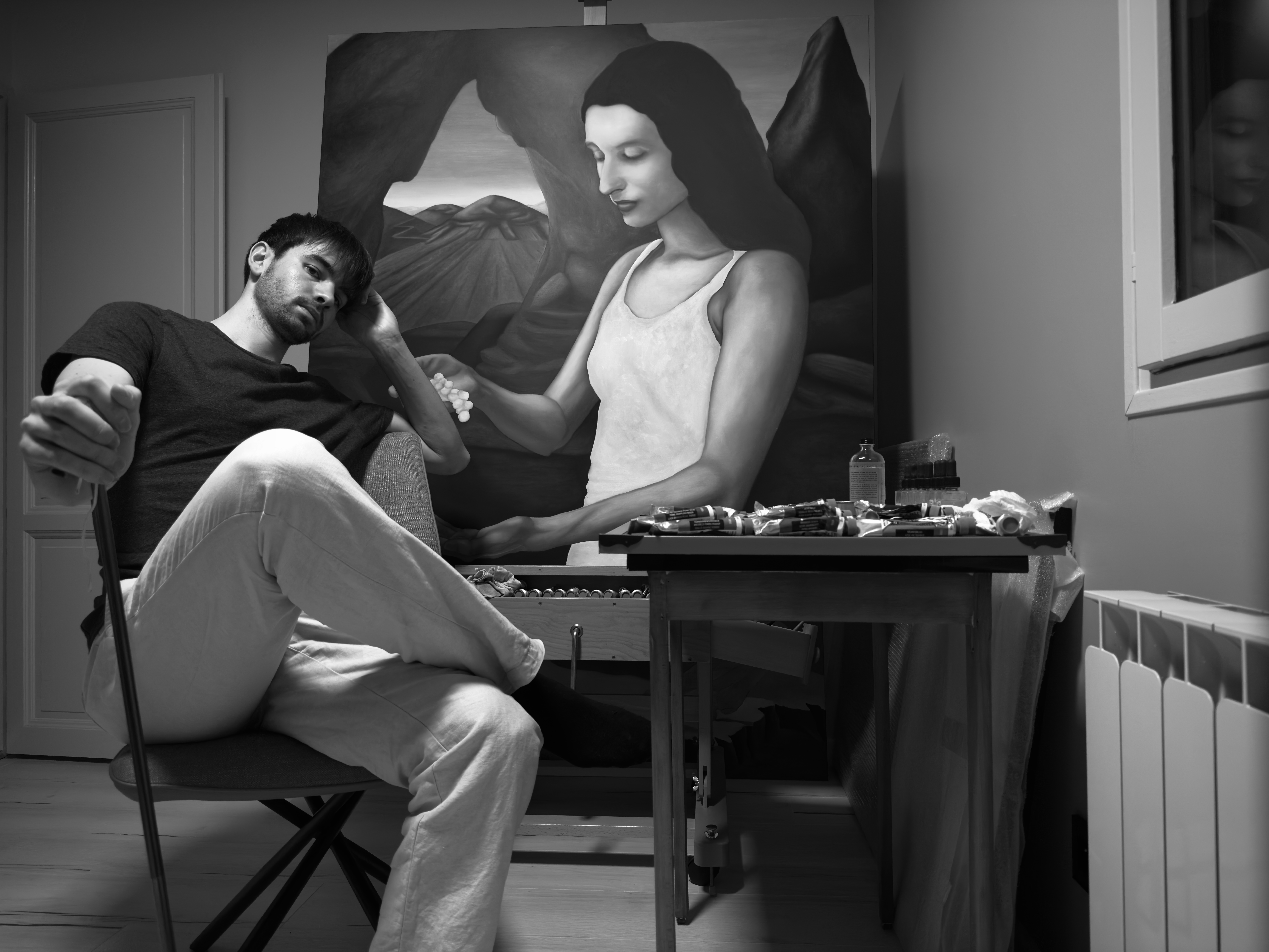 Théo Marichy dans son atelier tenant son appuie-main. A droite, son tableau "Le Temps et la Vigne, automne" de son triptyque "Le Temps et la Vigne". L'artiste bourguignon est dans atelier privé où il peint, dessine, sculpte.